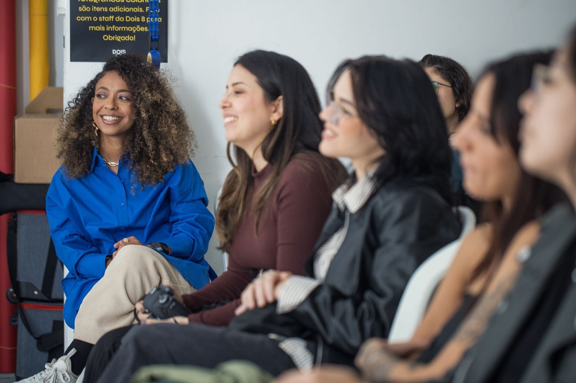 A diverse group of women engaged in a relaxed learning environment, smiling and engaged.